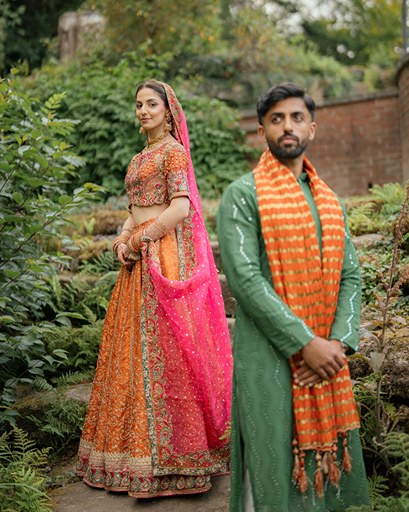 Couple in traditional attire, orange lehenga and green sherwani